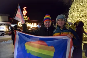 Kjera Griffith and her child, Augie Henrie, hold up a Wyoming state flag in the pride colors.