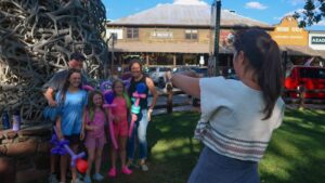 Town Councilor Alyson Spery takes a photo of a visiting family under one of town square’s antler arches. (Jenna McMurtry / KHOL)