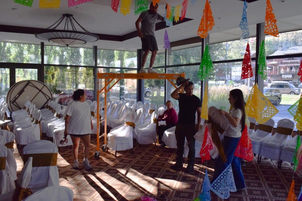 Elvis Hurtado spent the entire day atop the scaffolding. He and his wife Nidi Garcia have set up for family quinceñaras and baptisms in Jackson before and say taking down decorations, when they eat leftovers and “chill,” is always easier. ( Dante Filpula Ankney / KHOL)