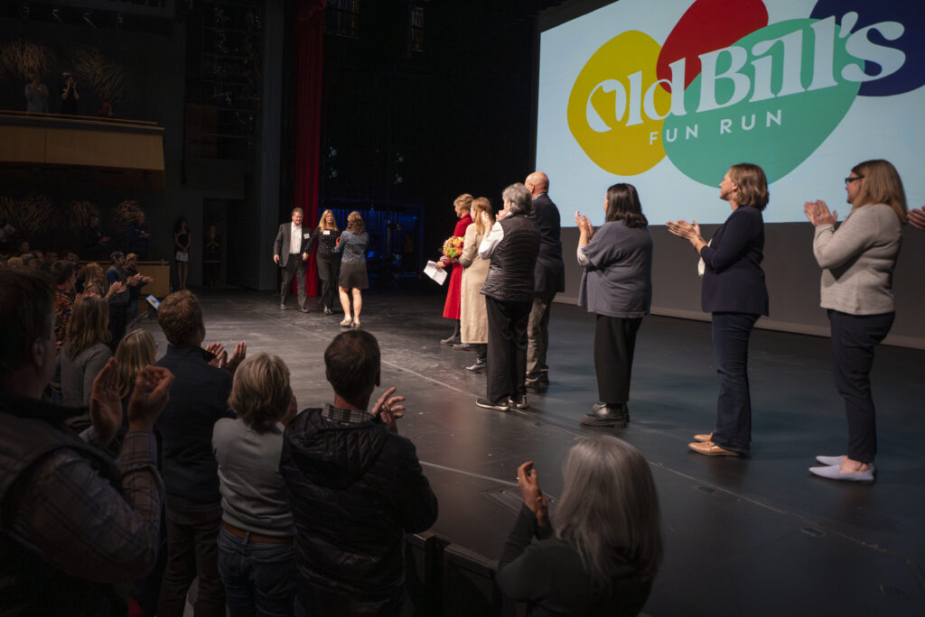 The Hugheses walk onto the Center for the Arts stage to accept the "The Spirit of Old Bill’s" award during an October 2023 awards party. (Kathryn Ziesig/Jackson Hole News&Guide)